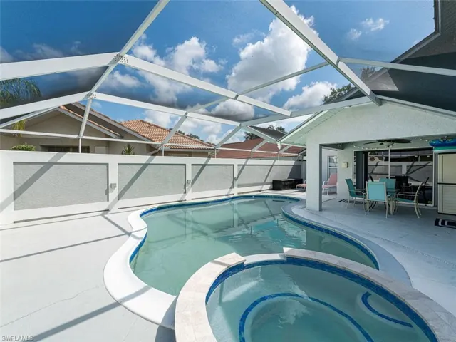 View of pool with glass enclosure, an in ground hot tub, and a patio