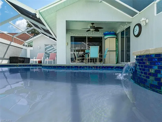View of pool with a patio, pool water feature, glass enclosure, and ceiling fan