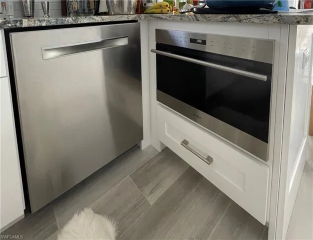 Kitchen view of stainless steel appliances, white cabinetry, and light wood finished floors