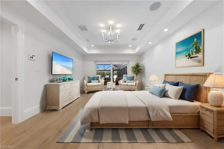 Bedroom featuring a chandelier, light wood-type flooring, and a raised ceiling
