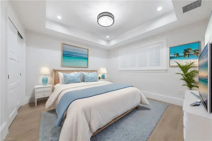 Bedroom with light wood-type flooring and a raised ceiling
