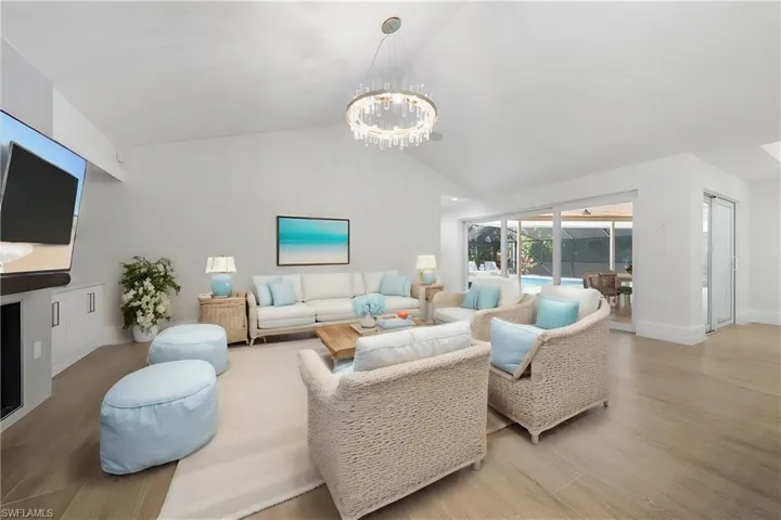 Living room with a chandelier, lofted ceiling, and light wood-type flooring