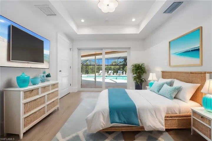Bedroom with access to exterior, a tray ceiling, and hardwood / wood-style flooring