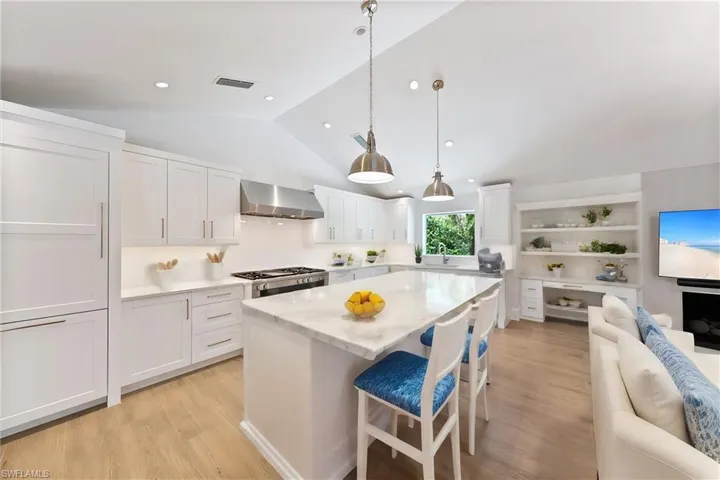 Kitchen with range, white cabinetry, light hardwood / wood-style flooring, and wall chimney exhaust hood