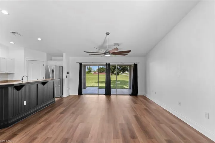 Unfurnished living room featuring ceiling fan, sink, hardwood / wood-style flooring, and vaulted ceiling