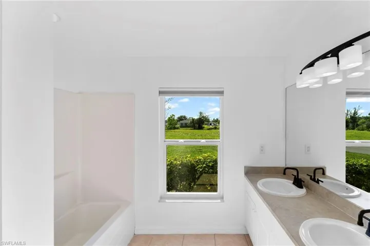 Bathroom with shower / washtub combination, dual vanity, and tile patterned flooring