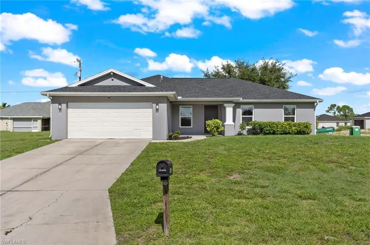 Ranch-style home featuring a garage and a front lawn