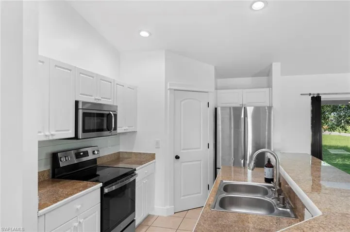 Kitchen featuring white cabinetry, stainless steel appliances, light tile patterned floors, and sink