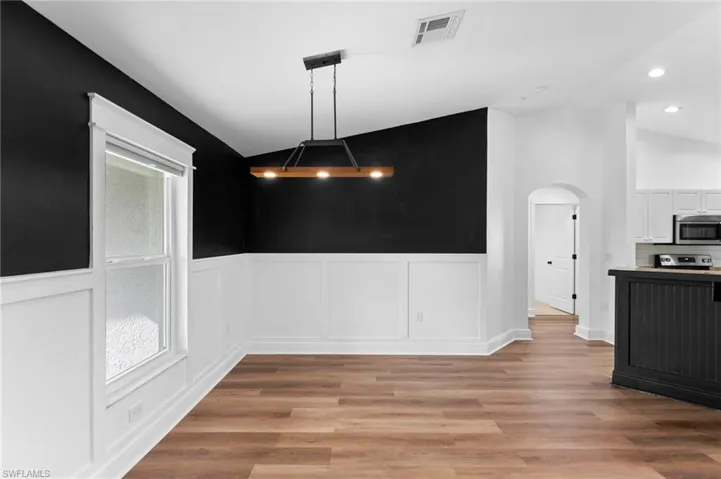Unfurnished dining area featuring lofted ceiling and light wood-type flooring
