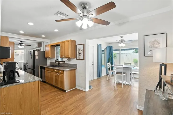 Kitchen featuring stainless steel appliances, a ceiling fan, light wood finished floors, ornamental molding, and recessed lighting