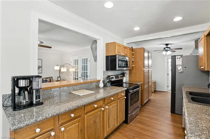 Kitchen with stainless steel appliances, a ceiling fan, light wood-type flooring, ornamental molding, and recessed lighting