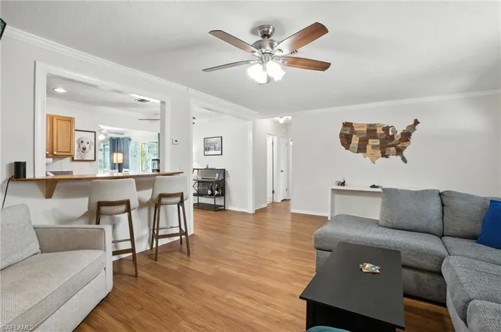 Living room with ornamental molding, a ceiling fan, and light wood-style floors