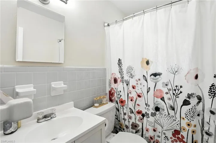 Bathroom with tile walls, curtained shower, vanity, and a wainscoted wall