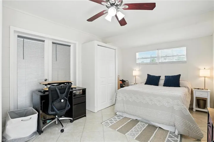 Bedroom featuring light tile patterned floors, an office area, a ceiling fan, and a closet