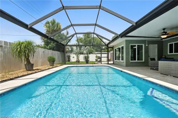View of swimming pool featuring a patio, a fenced backyard, a ceiling fan, outdoor lounge area, and glass enclosure