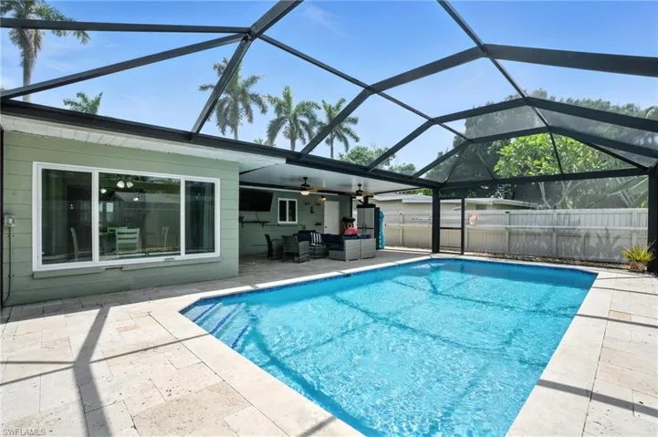 View of pool featuring a patio, ceiling fan, and glass enclosure