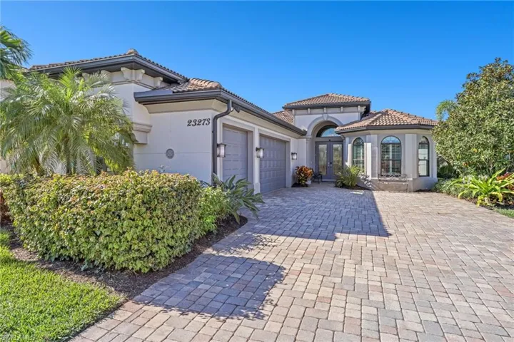 Mediterranean / spanish house with a garage, stucco siding, decorative driveway, a tiled roof, and french doors