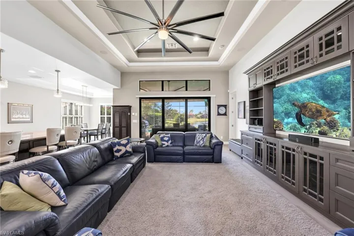 Living room with light colored carpet, a raised ceiling, and a high ceiling