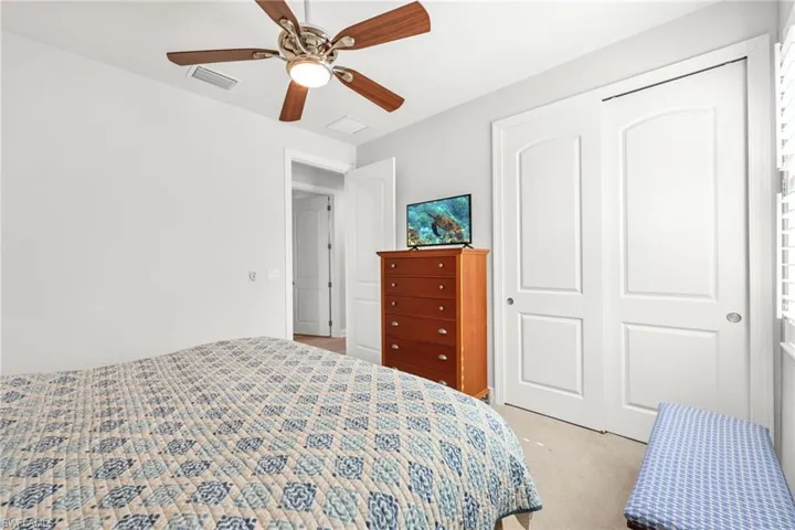 Bedroom with a closet, light carpet, and a ceiling fan
