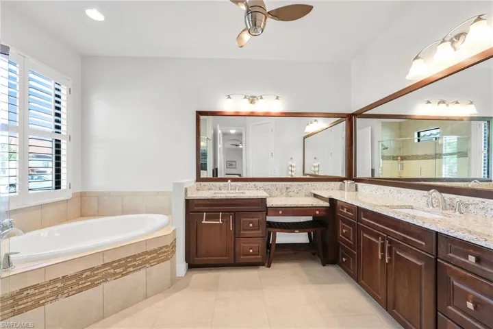 Full bathroom featuring double vanity, a bath, a ceiling fan, a stall shower, and light tile patterned flooring