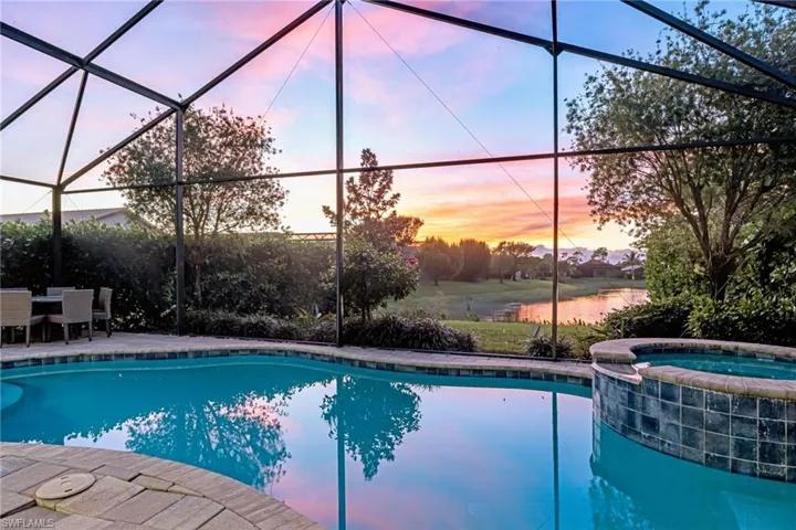 Pool at dusk with a lanai, a pool with connected hot tub, a sunroom, and a patio