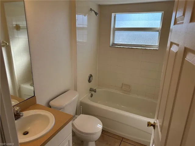 Full bathroom featuring vanity, tile patterned floors, tiled shower / bath combo, and toilet