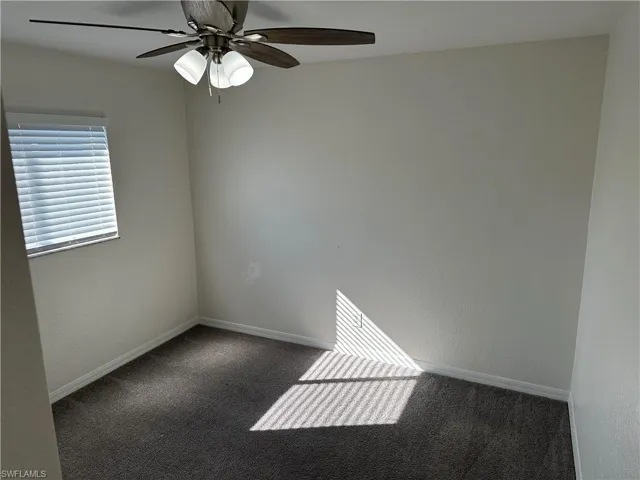 Spare room featuring dark carpet and ceiling fan