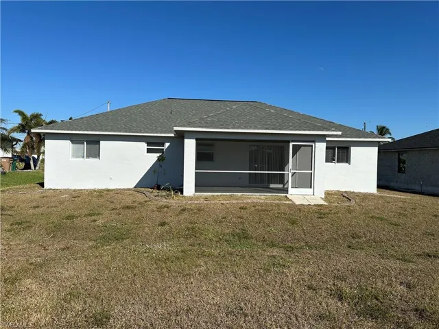 Rear view of property with a sunroom and a lawn