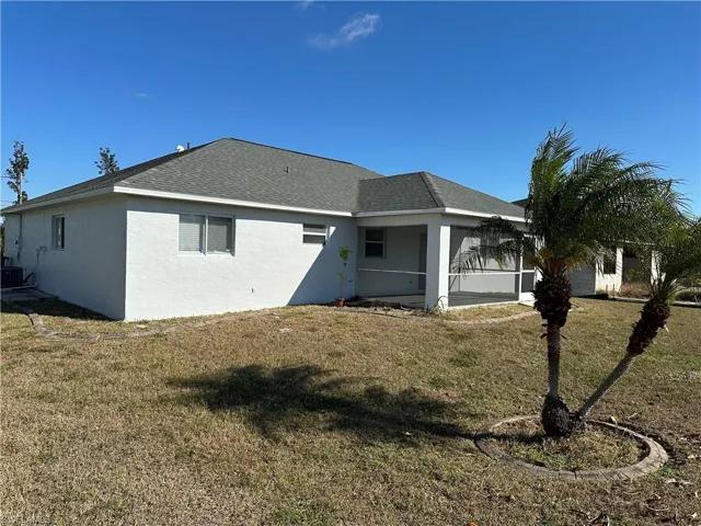 Back of property with a sunroom, a yard, and cooling unit
