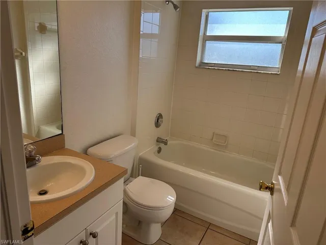 Full bathroom with tile patterned flooring, vanity, toilet, and tiled shower / bath