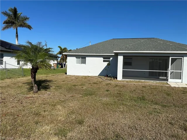 Rear view of house featuring a sunroom and a yard