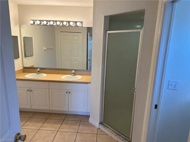 Bathroom featuring tile patterned flooring, vanity, and a shower with shower door