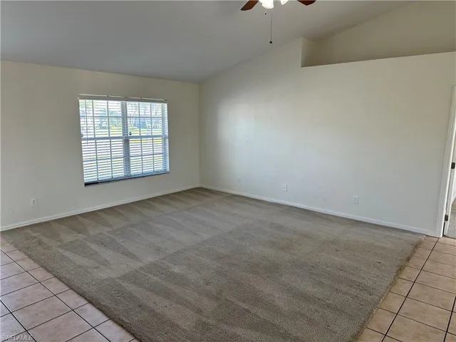 Spare room with light tile patterned floors, vaulted ceiling, and ceiling fan