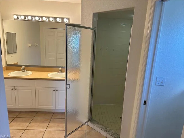 Bathroom featuring tile patterned flooring, vanity, and an enclosed shower