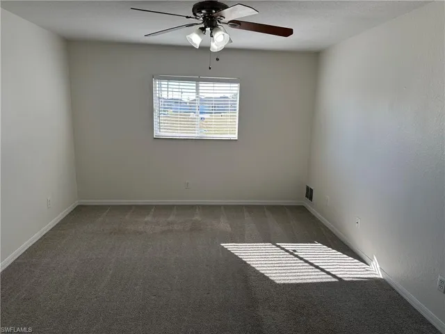 Carpeted empty room featuring ceiling fan