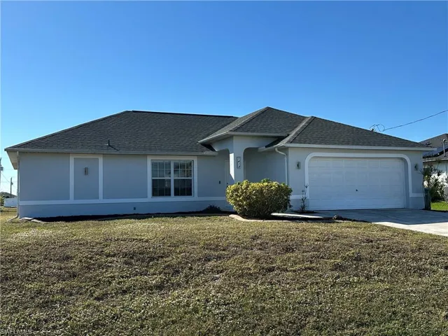 Ranch-style house featuring a garage and a front lawn