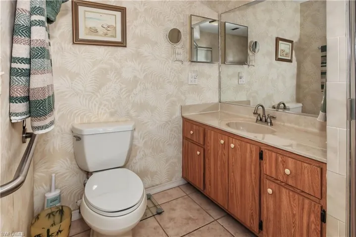 Bathroom featuring a vanity with a light-toned countertop, wood-finish cabinetry, a single basin sink, and a toilet