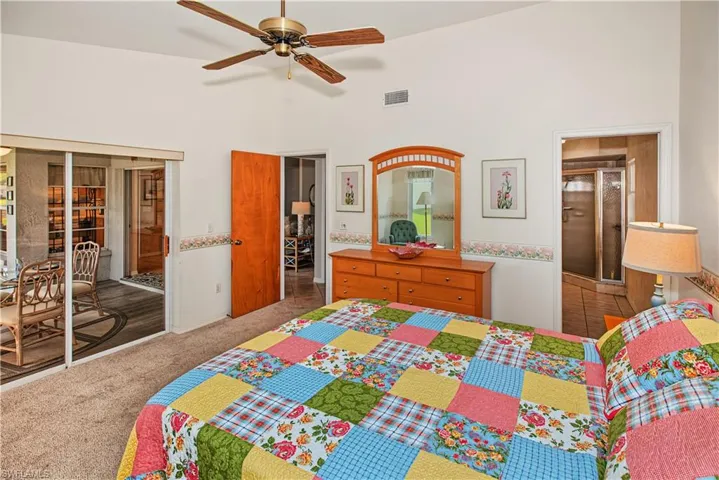 Vaulted ceiling with a ceiling fan, carpet flooring, a built-in shower enclosure, and sliding glass doors