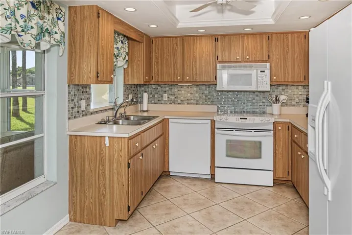 Kitchen featuring wood-finish cabinetry, a mosaic tile backsplash, and light-toned countertops