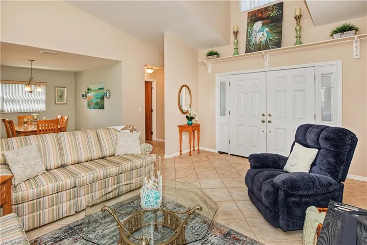 Vaulted ceilings, tiled flooring, double entry doors with transom windows, and a dining area with a chandelier