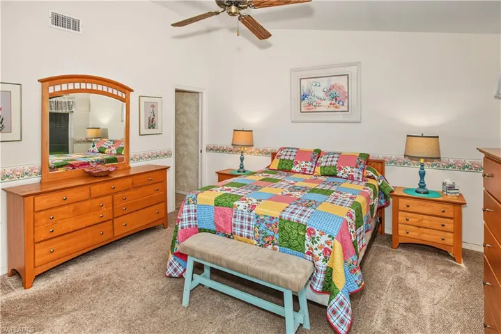 Vaulted ceiling with a ceiling fan, light-toned wall paint, and carpet flooring