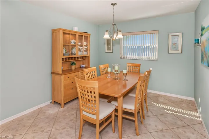 Tiled flooring, overhead chandelier, and a window with horizontal blinds