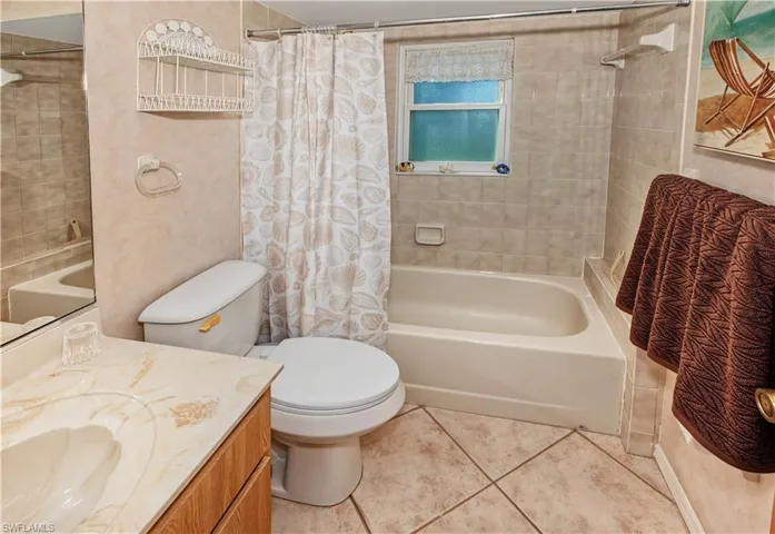Bathroom featuring a ceramic tile floor, tiled walls, built-in bathtub, and a vanity with an integrated sink
