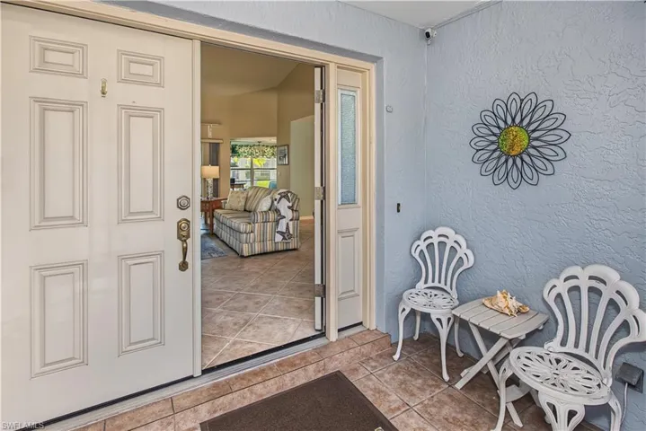 Entryway featuring double doors with decorative glass inserts, textured exterior wall, and tile flooring