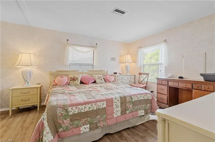 Bedroom with wallpapered walls and light wood-type flooring
