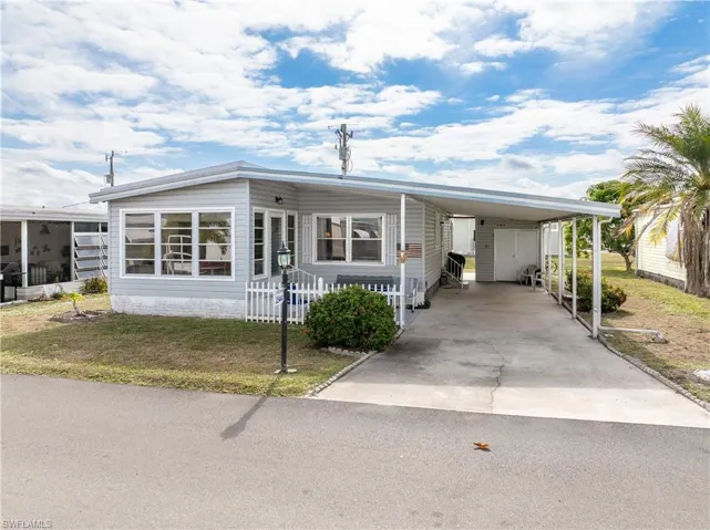 Manufactured / mobile home featuring an attached carport, a front yard, and concrete driveway