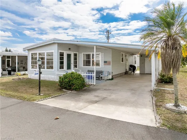Manufactured / mobile home featuring concrete driveway, an attached carport, and a front lawn