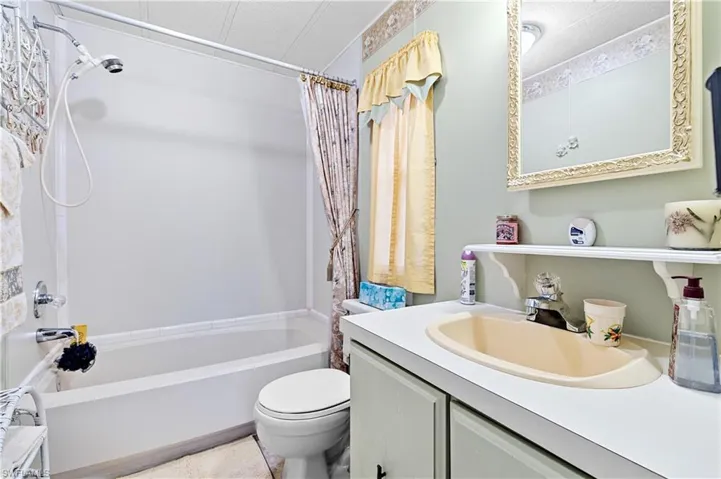 Bathroom featuring shower / bath combination with curtain, vanity, and a textured ceiling