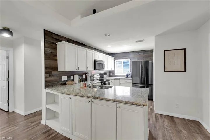 Kitchen with stainless steel appliances, granite countertops, a peninsula, and off-white cabinets