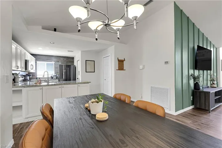 Dining room with suspended lighting and view into the open kitchen with peninsula